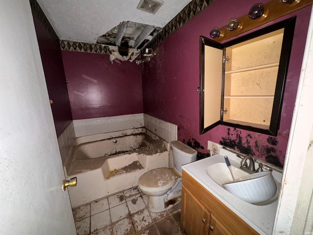 bathroom with a textured ceiling, toilet, vanity, and a bathtub