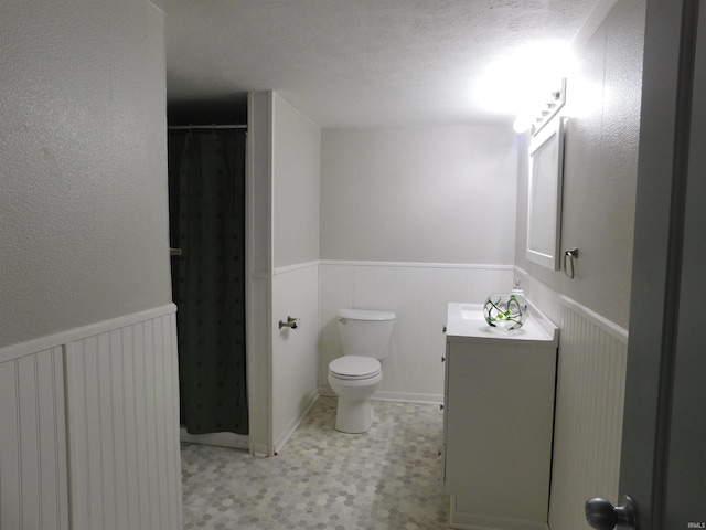 bathroom with vanity, toilet, a textured ceiling, and a shower with shower curtain