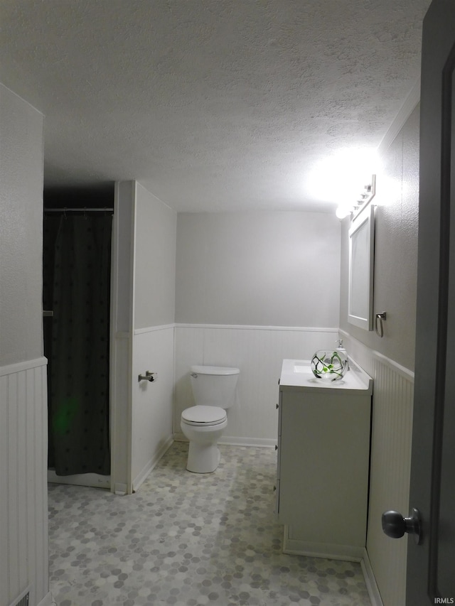 bathroom with vanity, toilet, a textured ceiling, and curtained shower