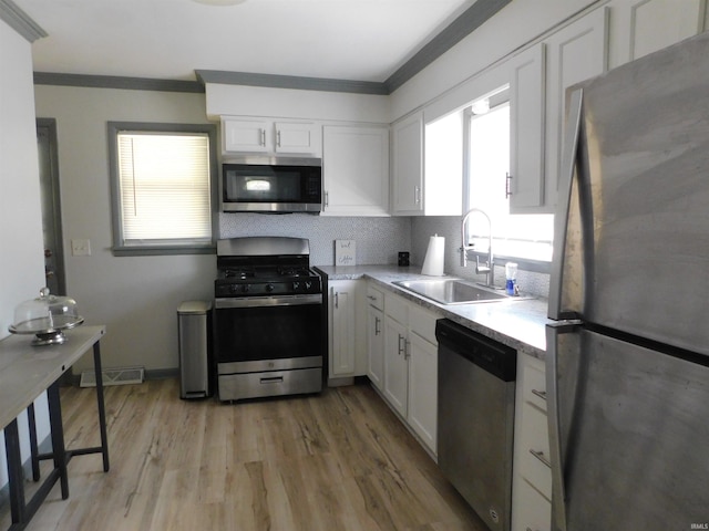 kitchen featuring white cabinetry, appliances with stainless steel finishes, a healthy amount of sunlight, and sink