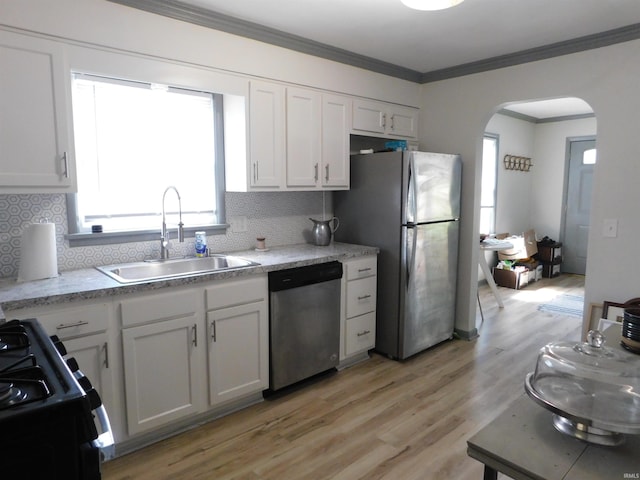 kitchen featuring light wood-type flooring, sink, white cabinets, stainless steel appliances, and backsplash