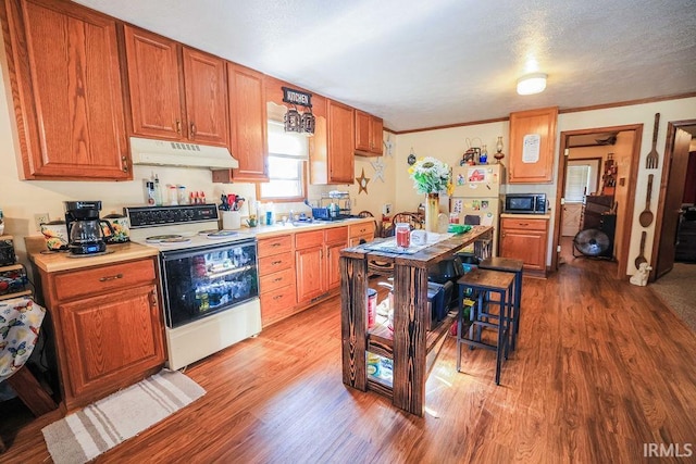 kitchen with a textured ceiling, white appliances, hardwood / wood-style flooring, and ornamental molding