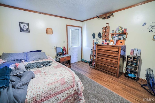 bedroom featuring hardwood / wood-style floors, ornamental molding, and a textured ceiling