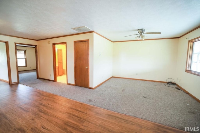 empty room featuring hardwood / wood-style floors, a wealth of natural light, ornamental molding, and ceiling fan