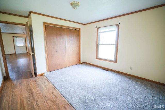 unfurnished bedroom featuring wood-type flooring, a closet, and crown molding