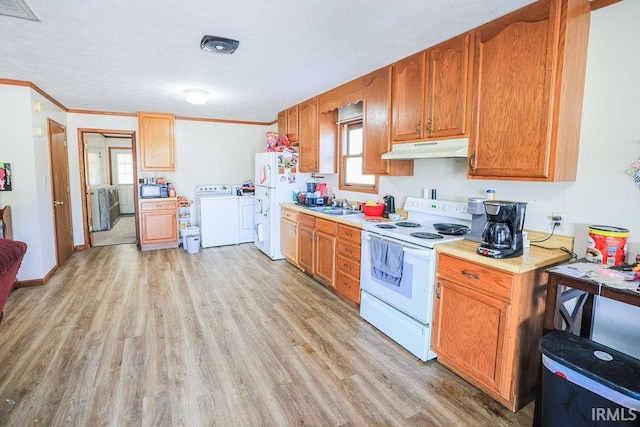 kitchen with white appliances, sink, light wood-type flooring, ornamental molding, and separate washer and dryer