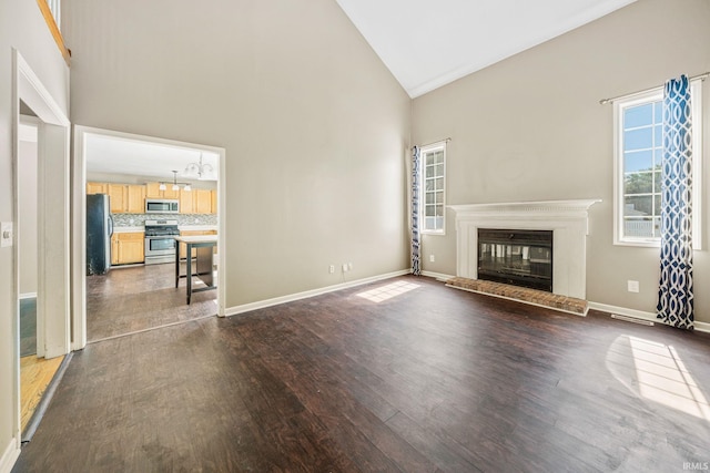 unfurnished living room featuring high vaulted ceiling and dark hardwood / wood-style flooring