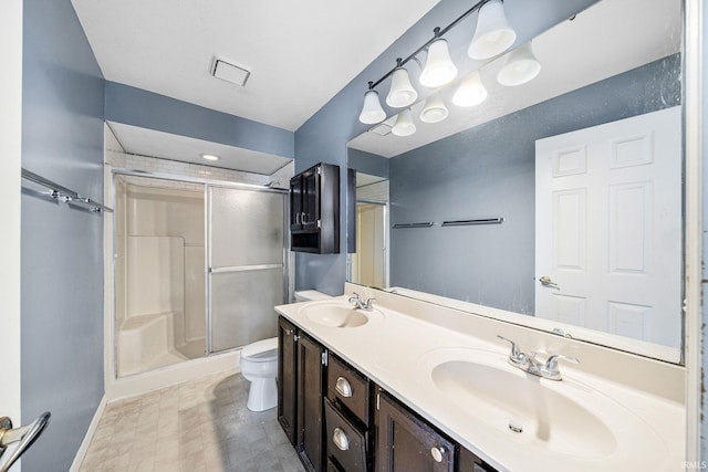 bathroom with vanity, toilet, and a shower with door