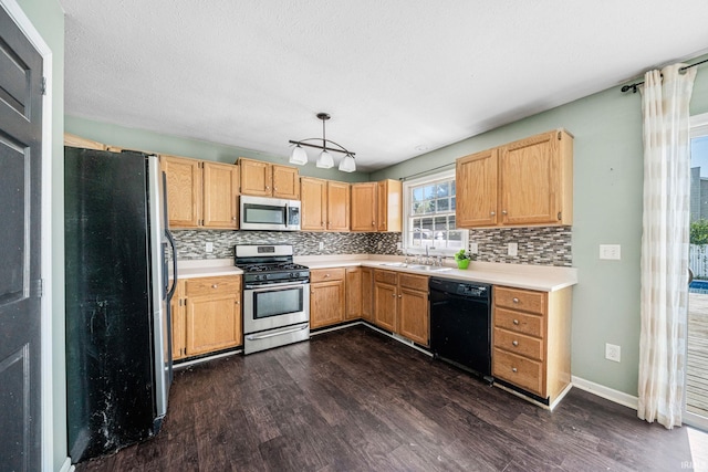 kitchen with appliances with stainless steel finishes, tasteful backsplash, dark wood-type flooring, and sink