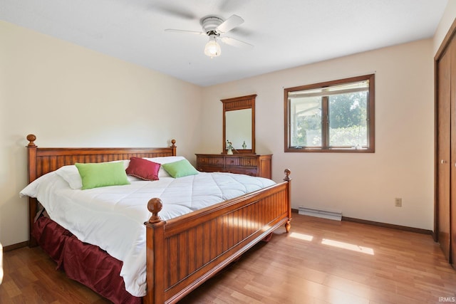 bedroom with ceiling fan, a closet, baseboard heating, and hardwood / wood-style floors