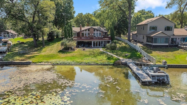 view of dock with a lawn and a water view