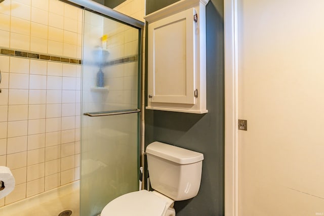 bathroom featuring toilet and a shower with shower door