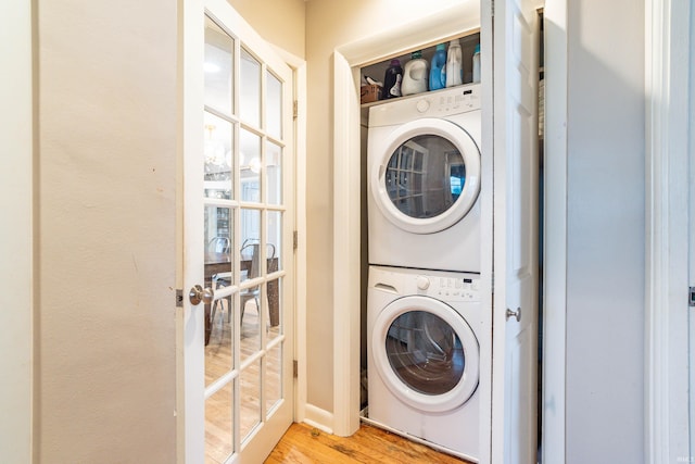 laundry room featuring light wood-type flooring and stacked washer / dryer