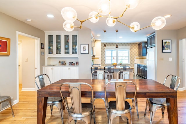 dining room with light wood-type flooring and a chandelier