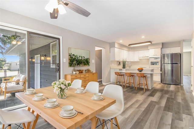 dining space with ceiling fan, light wood-type flooring, and sink