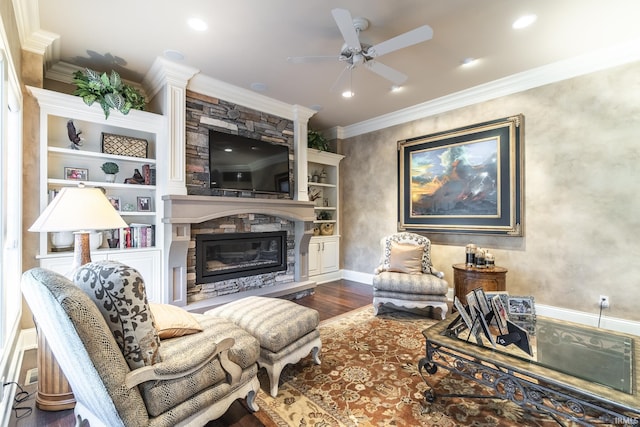 living room with ceiling fan, ornamental molding, a stone fireplace, recessed lighting, and wood finished floors