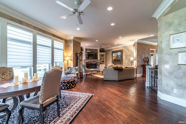 dining space featuring a healthy amount of sunlight, ceiling fan, dark wood-type flooring, and a stone fireplace