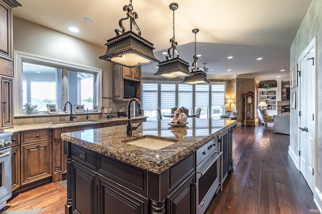 kitchen featuring dark wood finished floors, recessed lighting, open floor plan, and a sink