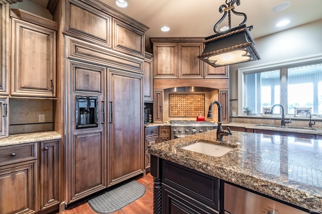 kitchen featuring decorative backsplash, paneled built in refrigerator, pendant lighting, dark hardwood / wood-style floors, and sink