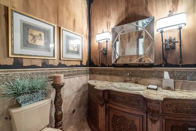 bathroom featuring vanity, tile walls, and toilet