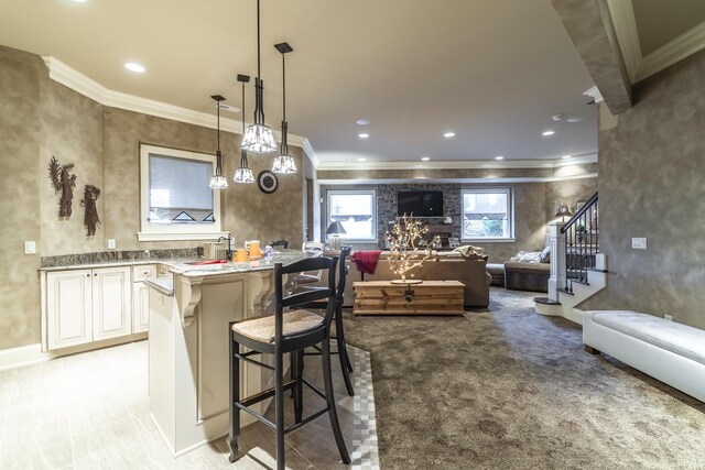 kitchen featuring light stone counters, a breakfast bar area, light colored carpet, decorative light fixtures, and crown molding