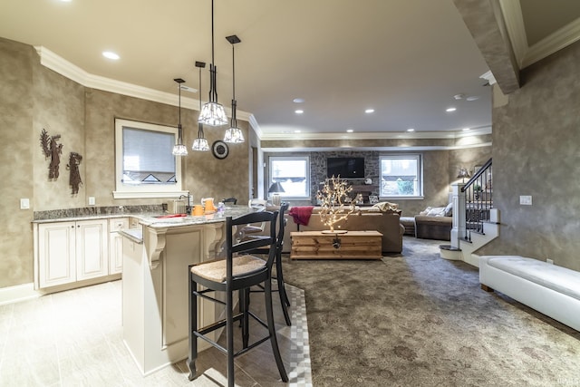 kitchen featuring a kitchen breakfast bar, open floor plan, crown molding, and hanging light fixtures
