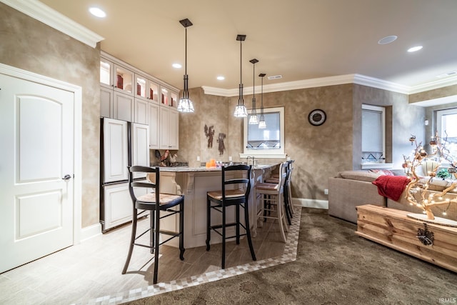 interior space featuring light stone countertops, pendant lighting, a kitchen bar, a center island, and ornamental molding