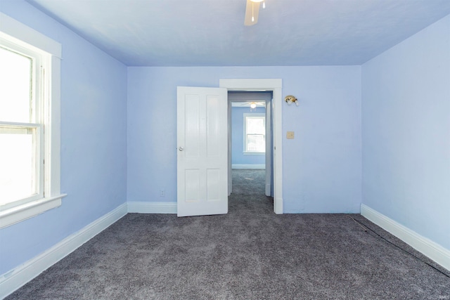 empty room featuring dark carpet and ceiling fan