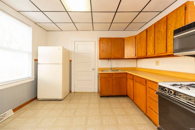 kitchen with white refrigerator, gas range, a healthy amount of sunlight, and sink