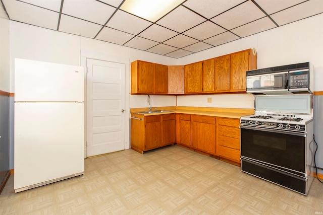 kitchen with light parquet flooring, stove, sink, and white refrigerator