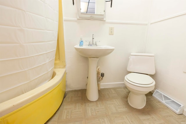 bathroom featuring parquet flooring, shower / tub combo, and toilet