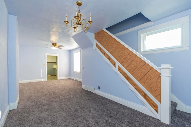 interior space featuring ceiling fan with notable chandelier and dark carpet