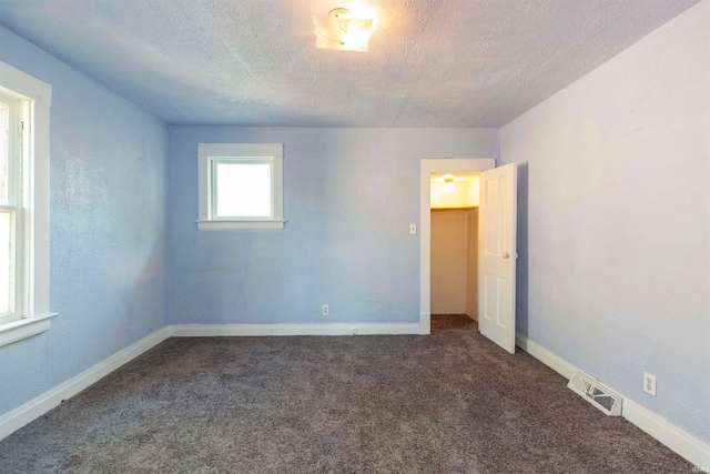 carpeted empty room featuring a textured ceiling