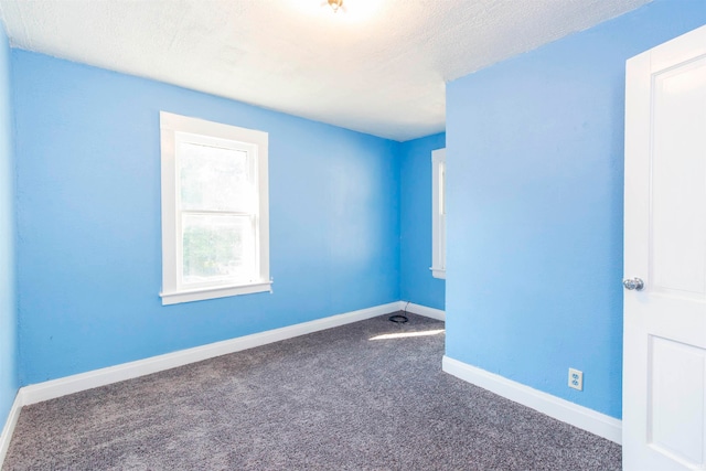 empty room featuring a textured ceiling and dark colored carpet