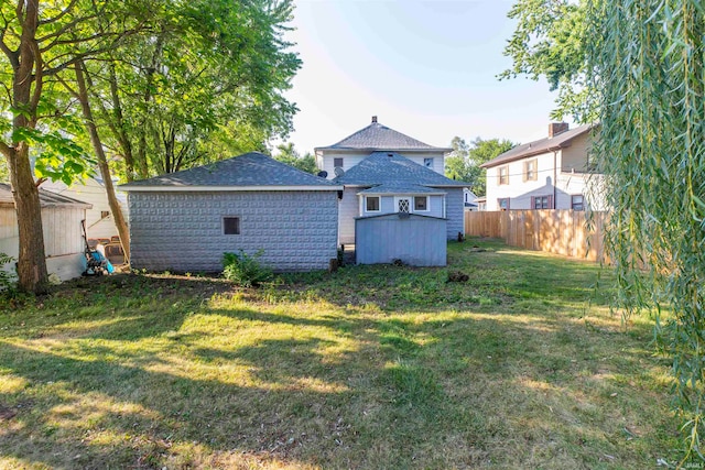 rear view of property with a yard and a storage unit