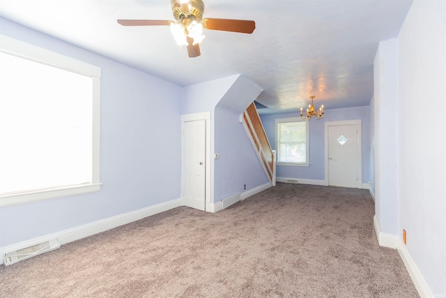 entrance foyer featuring ceiling fan with notable chandelier and light carpet