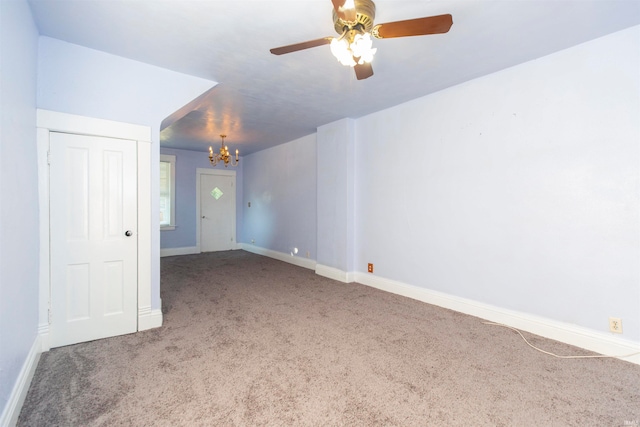 empty room with ceiling fan with notable chandelier and carpet floors