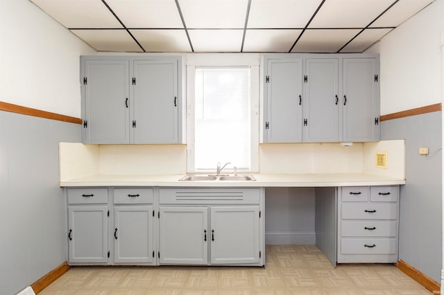 kitchen featuring light parquet flooring, a drop ceiling, and sink