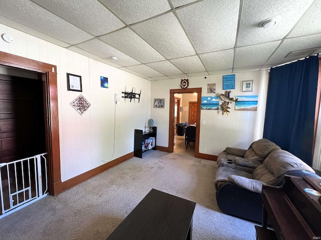 unfurnished living room with carpet, a paneled ceiling, and wooden walls