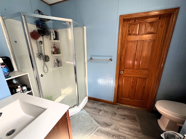 bathroom with hardwood / wood-style floors, toilet, a shower with door, and sink