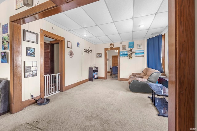 living area featuring carpet flooring and a drop ceiling