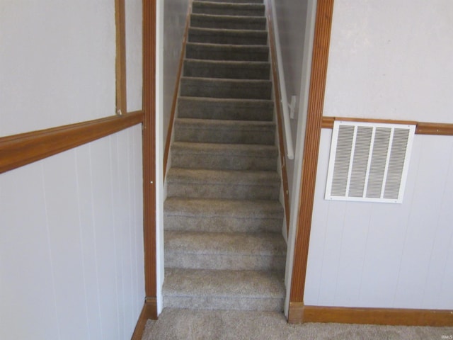 stairs with carpet floors and wood walls