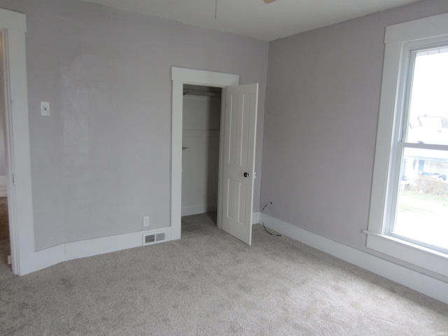 spare room featuring ceiling fan, light colored carpet, and a wealth of natural light