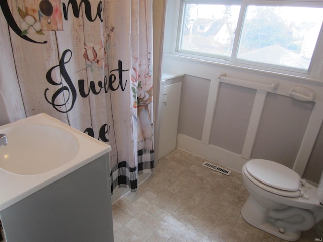 bathroom featuring a shower with shower curtain, plenty of natural light, vanity, and toilet