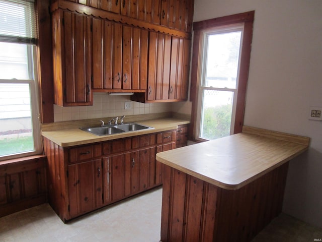 kitchen featuring tasteful backsplash, sink, kitchen peninsula, and a wealth of natural light