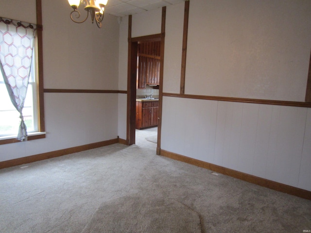 carpeted spare room with a notable chandelier