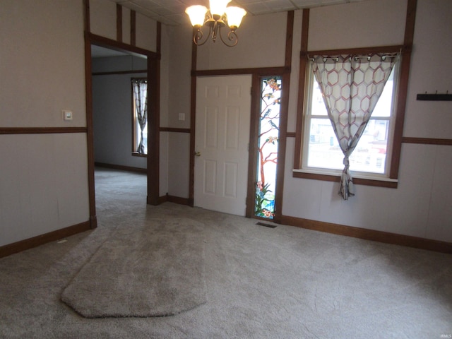 foyer entrance featuring carpet floors and a notable chandelier