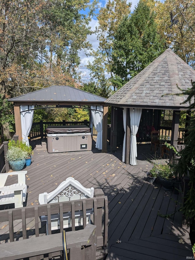 deck featuring a hot tub and a gazebo