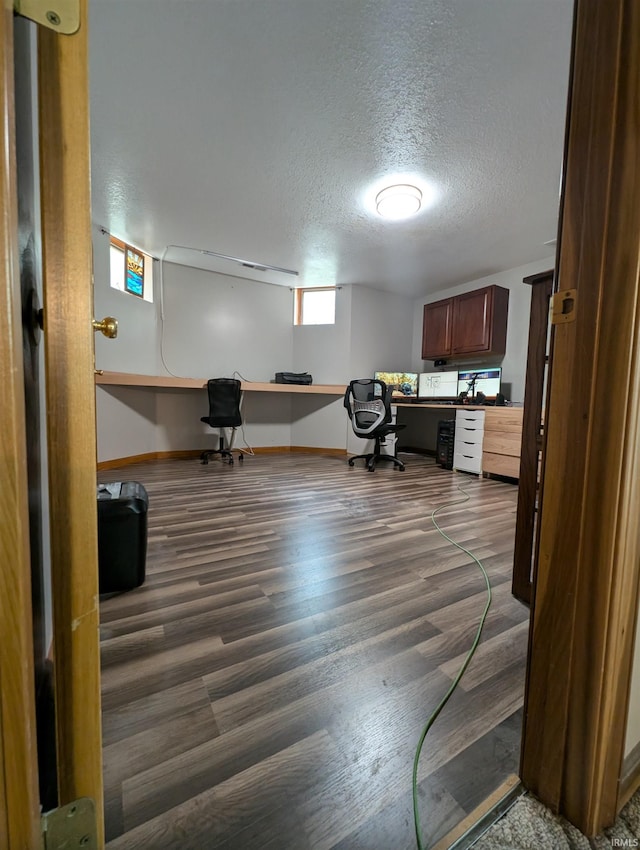 interior space with built in desk, a textured ceiling, and dark hardwood / wood-style flooring