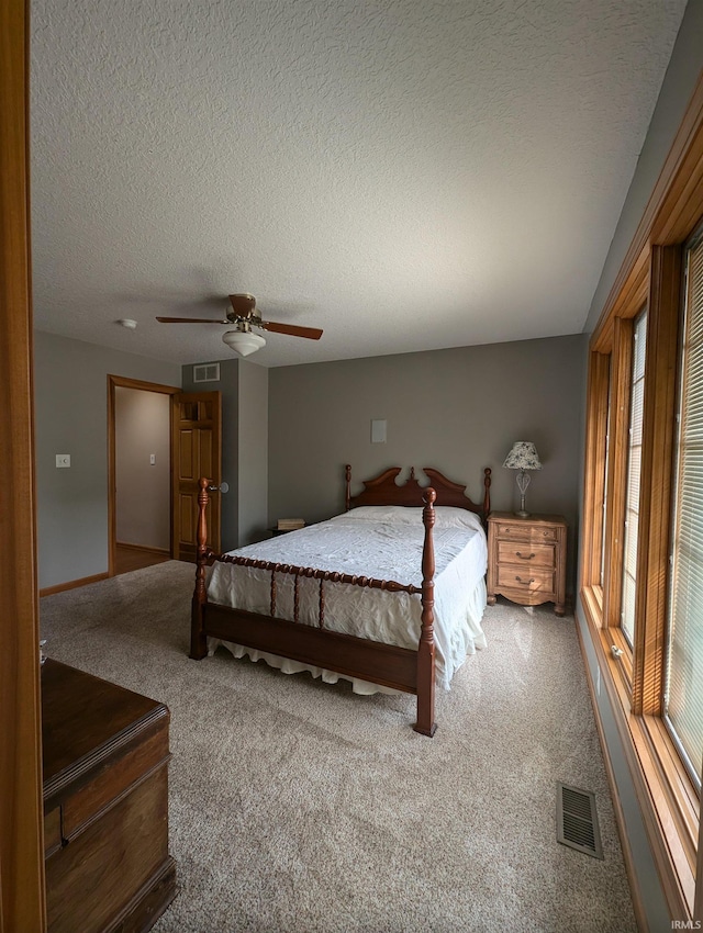 carpeted bedroom with ceiling fan and a textured ceiling